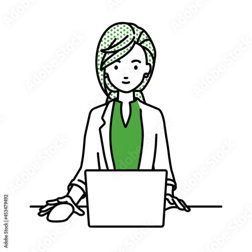 デスクで座ってPCを使っているジャケットの女性