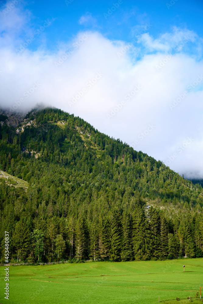 Mountain in the Austrian Alps with blue sky above and white clouds around the mountain.