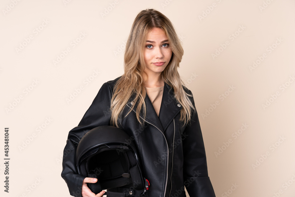 Russian girl with a motorcycle helmet isolated on beige background with sad and depressed expression Russian girl with a motorcycle helmet isolated on beige background with sad and depressed expression