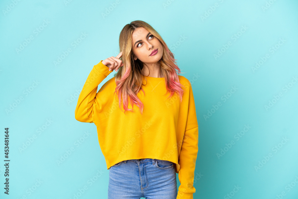 Young woman over isolated blue background making the gesture of madness putting finger on the head Young woman over isolated blue background making the gesture of madness putting finger on the head