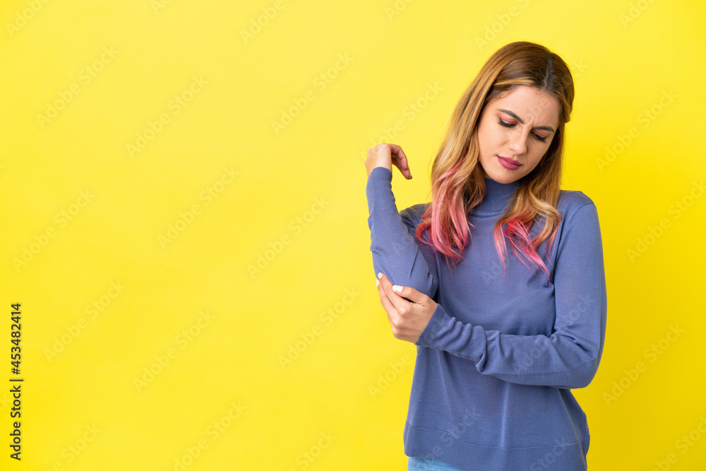 Young woman over isolated yellow background with pain in elbow Young woman over isolated yellow background with pain in elbow