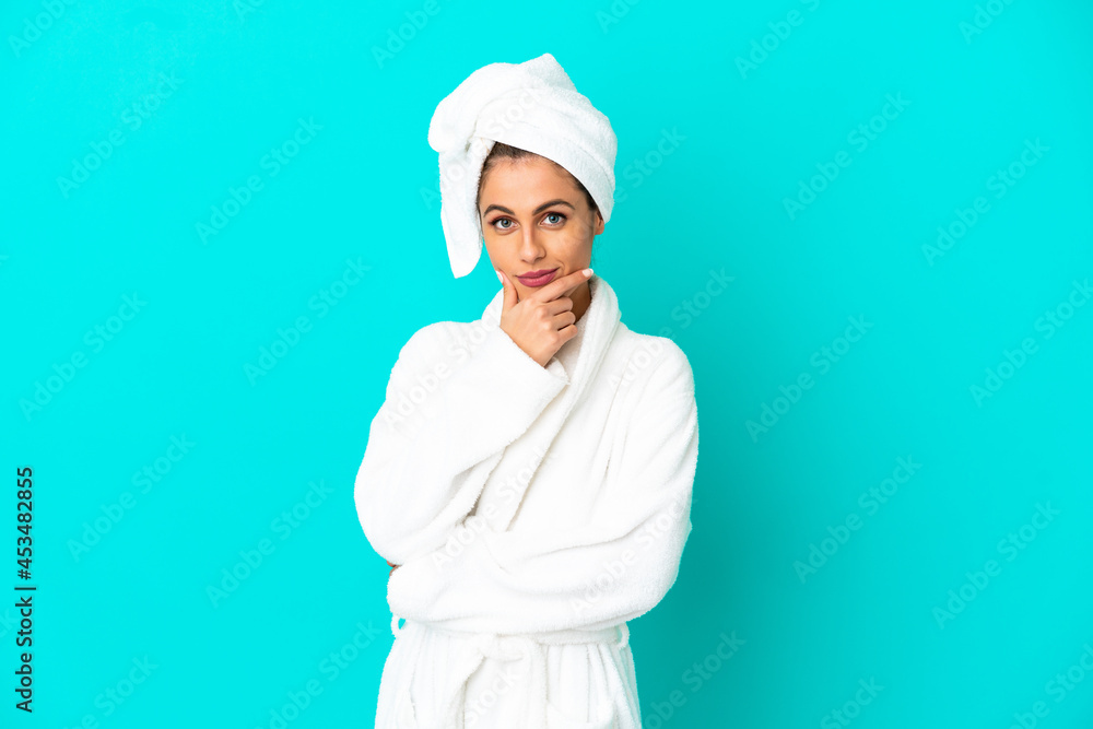 Young woman in a bathrobe over isolated blue background thinking Young woman in a bathrobe over isolated blue background thinking
