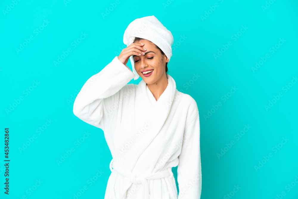Young woman in a bathrobe over isolated blue background laughing Young woman in a bathrobe over isolated blue background laughing