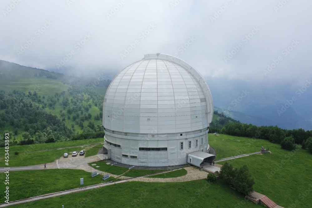 Obraz premium Nizhny Arkhyz, Russia - June 26, 2021: Aerial view of Astrophysical observatory of the Russian Academy of Sciences in Caucasus. BTA tower. Cloudy. Scenic landscape, cosmos, astronomy concept. Summer