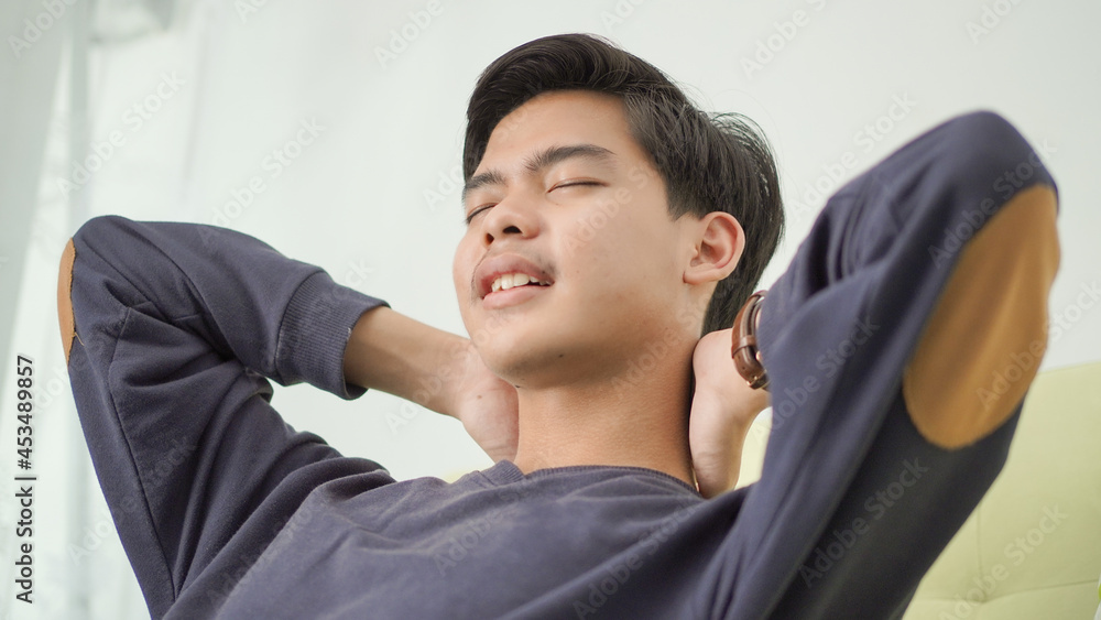 tired asian young man closing his eyes looking for ideas at home tired asian young man closing his eyes looking for ideas at home