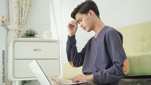 asian man thinking image on his laptop screen at home