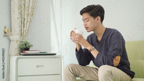 young asian man enjoying a drink at home after work