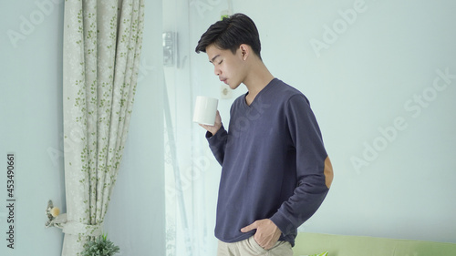 handsome man standing drinking a glass of drink at home photo