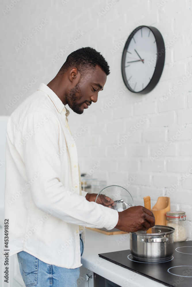 side view of young african american man cooking in kitchen side view of young african american man cooking in kitchen
