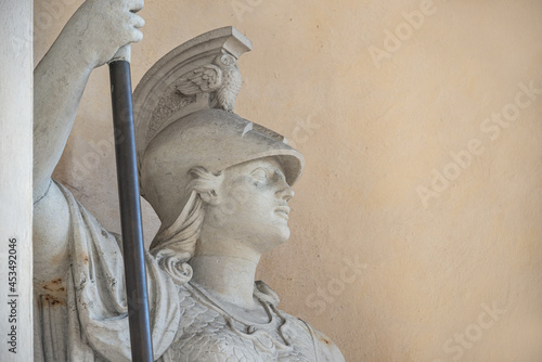 Old statue of a sensual Roman woman warrior, Amazonian, as defender with spear and helmet, details, closeup, with copy space.