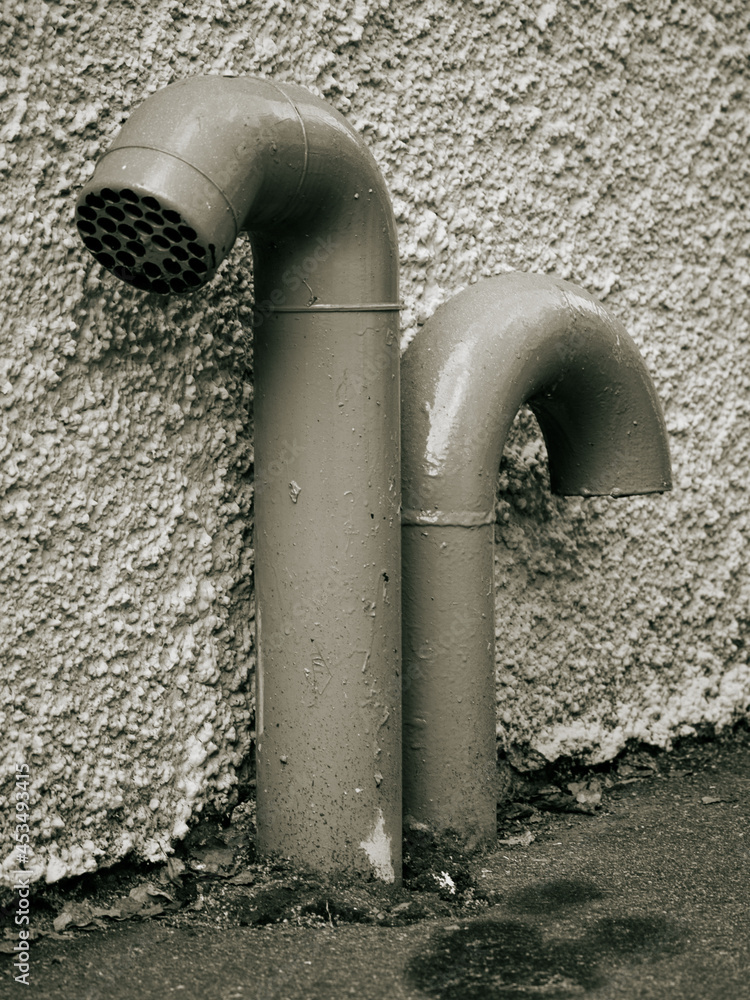 A tinted monochromatic image of drain pipes against a wall A tinted monochromatic image of drain pipes against a wall