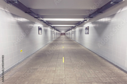 Underground pedestrian crossing in the city illuminated by artificial white light. Stairs at the end of the tunnel. Road separation, traffic direction due to Covid. Pedestrian crossing in the metro.