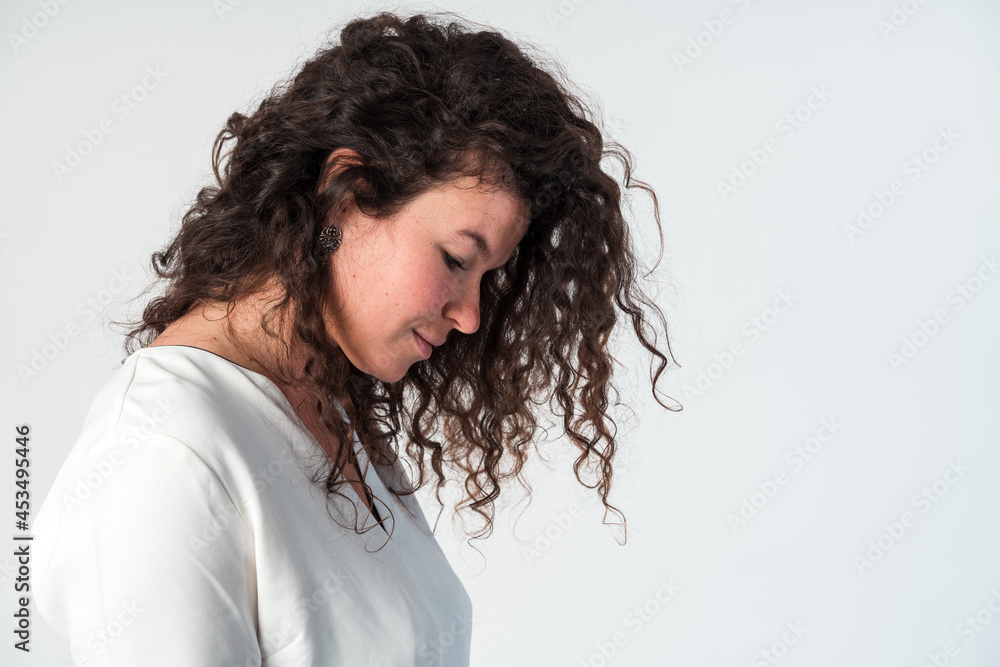 So tender. Profile side view portrait of calm serious beautiful brunette caucasian woman in casual white blouse with nude makeup standing and looking down So tender. Profile side view portrait of calm serious beautiful brunette caucasian woman in casual white blouse with nude makeup standing and looking down