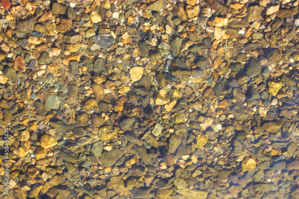 Close-up and top view of shiny transparent yellow sand and stones on the beach with clear water. clear sea, the river reveals the beauty of a natural resting place in the summer under the sun. Has a Close-up and top view of shiny transparent yellow sand and stones on the beach with clear water. clear sea, the river reveals the beauty of a natural resting place in the summer under the sun. Has a