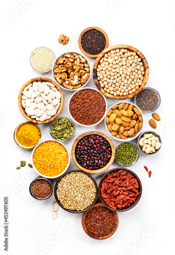 Set of superfoods, legumes, cereals, nuts, seeds in bowls on white table. Copy space, top view