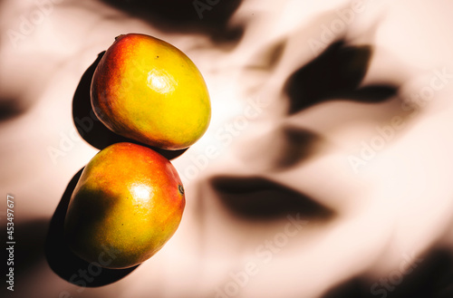 Summer mango fruits top view. Contemporary still life, lpink  background, hard light and shadow pattern photo