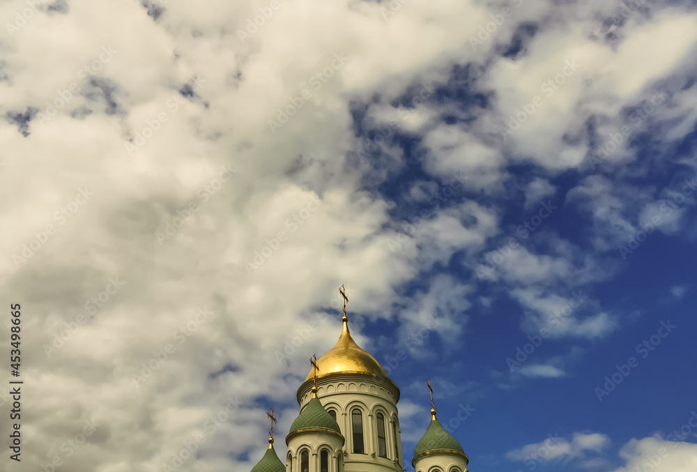 Domes of the temple against the background of a bright blue sky with clouds