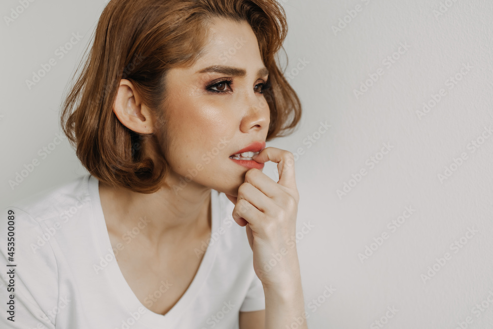 Asian woman is biting her nails alone in her apartment. Concept of emotional. Asian woman is biting her nails alone in her apartment. Concept of emotional.