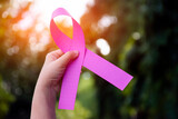 Asian young female holds pink paper ribbon in the back, concept for supporting breast cancer campaign around the world.