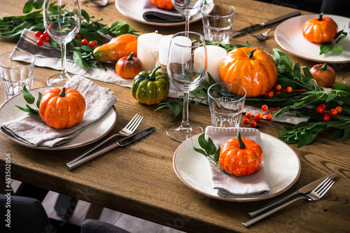 Autumn table setting with plate, glass, cutlery and autumn decor at wooden table. Thanksgiving food festive dinner concept. photo