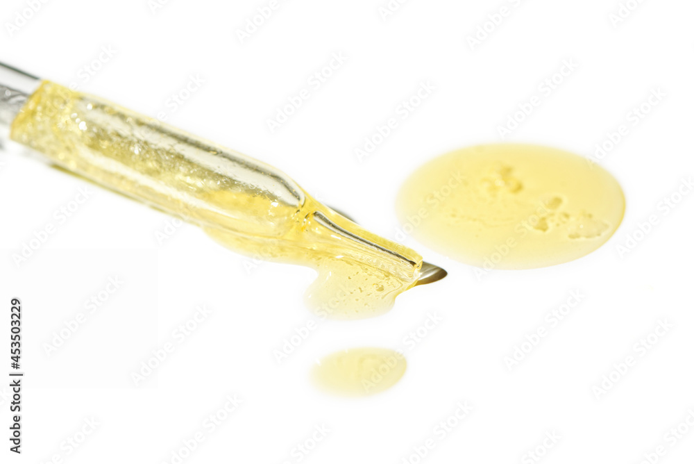 Liquid oil serum drop in pipette isolated on white background. Retinol, aha, bha acid, collagen skincare fluid, photo with shallow depth of field. Gold essence in dropper for beauty treatment Liquid oil serum drop in pipette isolated on white background. Retinol, aha, bha acid, collagen skincare fluid, photo with shallow depth of field. Gold essence in dropper for beauty treatment