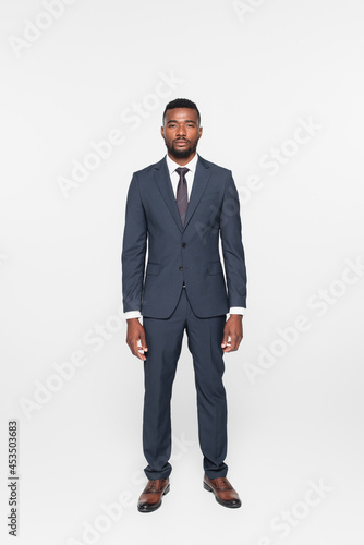 full length of african american businessman in suit isolated on grey