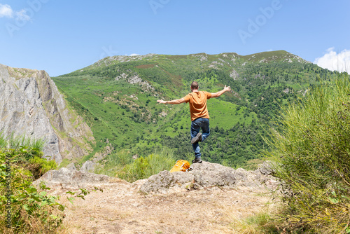 Young man in balance at the top of a mountain looking at the views. Active vacation. 