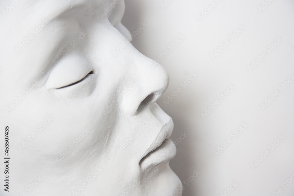 Portrait of a white face on a white background. Detail of sculpture with closed eyes. Portrait of a white face on a white background. Detail of sculpture with closed eyes.