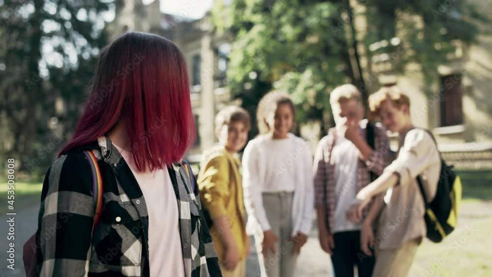 Group of school children bullying sad unpopular girl for distinctive appearance Group of school children bullying sad unpopular girl for distinctive appearance