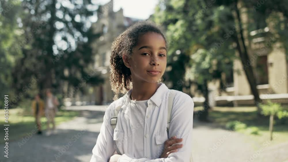 Confident biracial school girl posing on camera with arms crossed on chest Confident biracial school girl posing on camera with arms crossed on chest