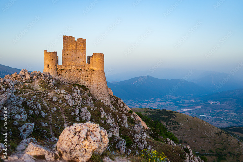 Castle ruins on mountain top at Rocca Calascio, italian travel destination, landmark in the Gran Sasso National Park, Abruzzo, Italy. Clear blue sky at dusk