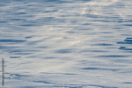 Snowy background, snow-covered surface of the earth after a blizzard in the morning in the sunlight with distinct layers of snow