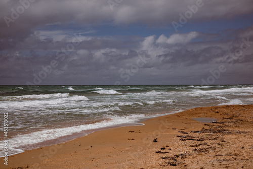 Sea waves beating against the sandy shore. Stormy ocean landscape. Vacation and travel.