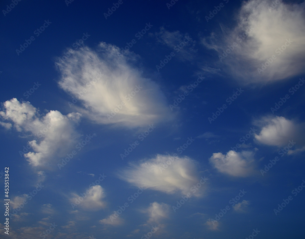 Fototapeta premium Scattered white clouds at dawn with intense blue sky in the background