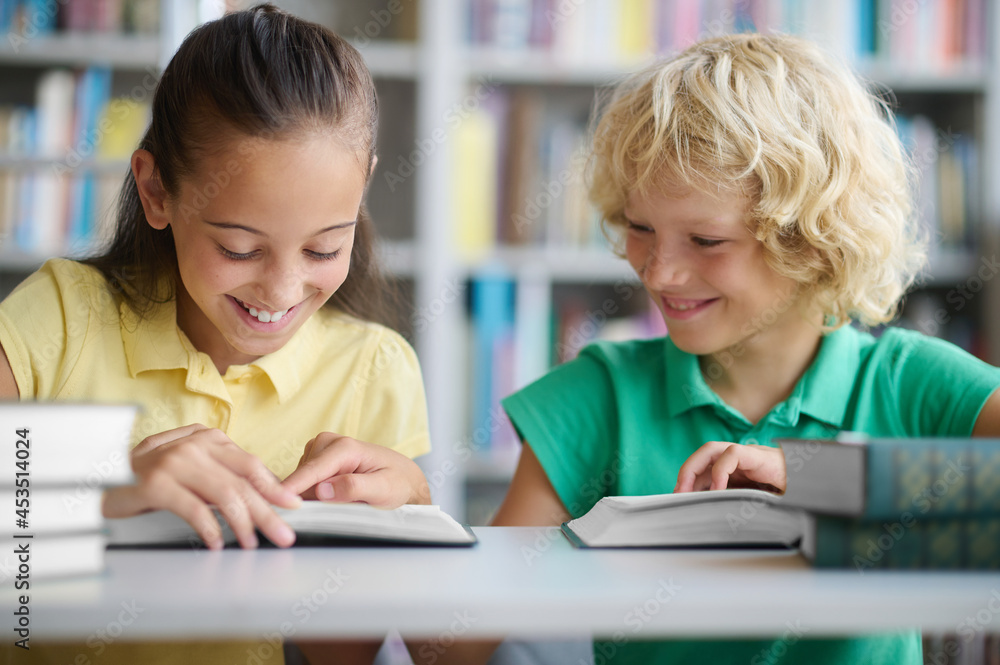 Two joyful classmates studying together at a public library Two joyful classmates studying together at a public library
