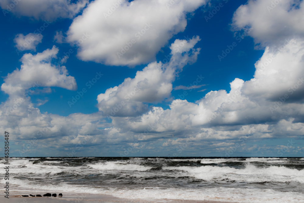 Vacation by the sea, ocean, beach, waves and beautiful sky. Strong wind and white clouds over the sea somewhere in Poland