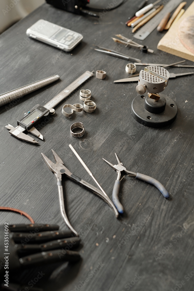Fototapeta premium Close-up of jewelers tools including pliers and measuring tools placed on wooden table with ring blanks