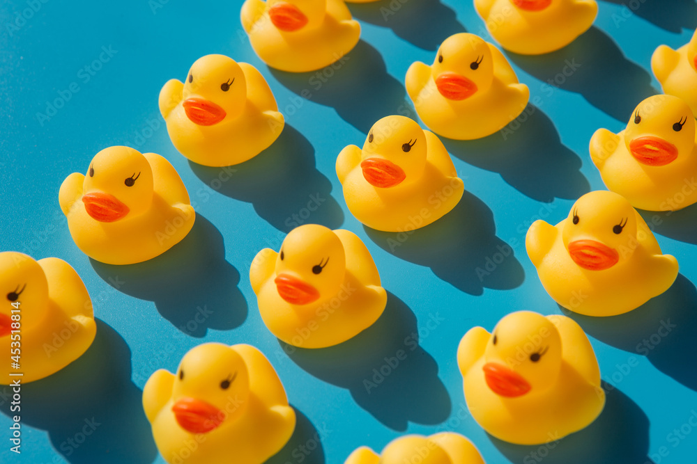 yellow rubber ducks on a blue background with hard shadows