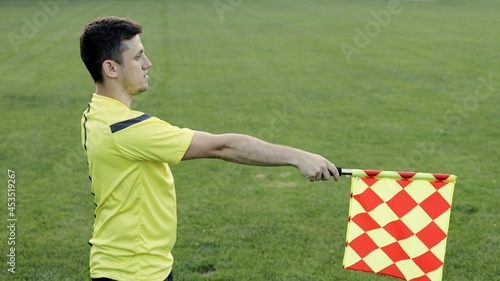 Assistant referee moving along the sideline during a soccer match. Linesman hand with flag signalling for offside trap to referee during football match. photo