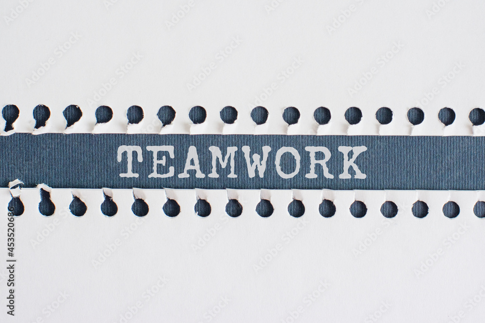 Torn paper strip on blue background with text TEAMWORK