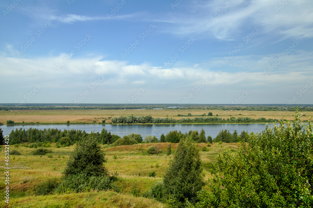 View from the mountain to the Oka River on a clear summer day. A horizontally flowing river. Horizon and hills. The village of Konstantinovo. View from the mountain to the Oka River on a clear summer day. A horizontally flowing river. Horizon and hills. The village of Konstantinovo.