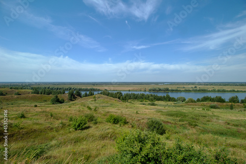 View from the mountain to the Oka River on a clear summer day. The river flows at an angle. Horizon and hills. The village of Konstantinovo.