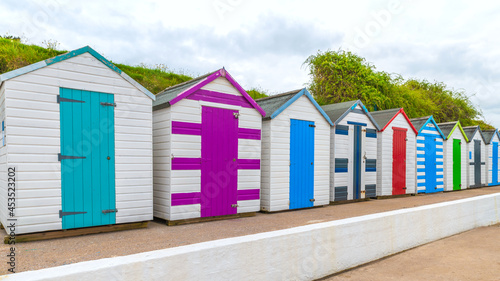 Colourful beach houses. Row of multicolored beach huts against blue sky.