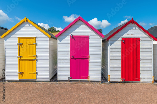 Colourful beach houses. Row of multicolored beach huts against blue sky.