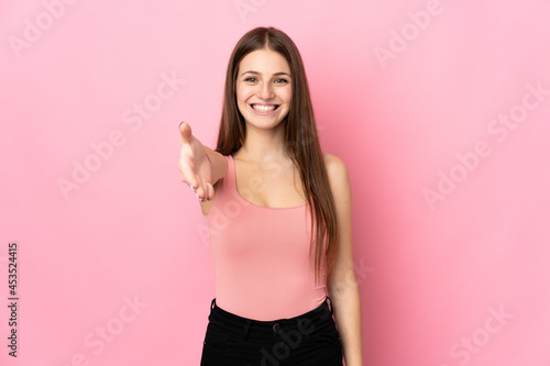 Young caucasian woman isolated on pink background shaking hands for closing a good deal