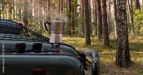 Making coffee outdoors. Coffee maker on portable stove and two cups on tourist car hood.  photo