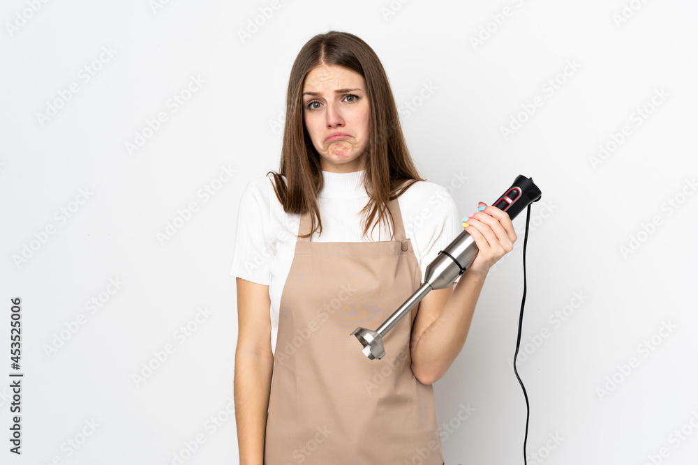 Young woman using hand blender isolated on white background pleading Young woman using hand blender isolated on white background pleading