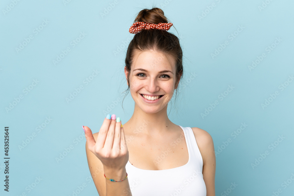 Young caucasian woman isolated on blue background inviting to come with hand. Happy that you came Young caucasian woman isolated on blue background inviting to come with hand. Happy that you came