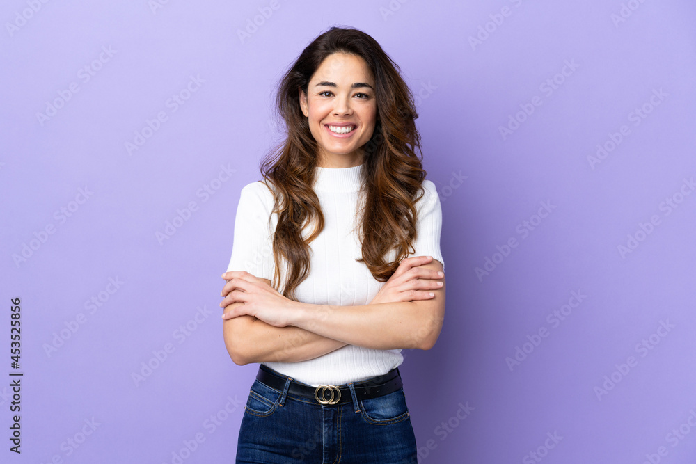 Woman over isolated purple background keeping the arms crossed in frontal position Woman over isolated purple background keeping the arms crossed in frontal position