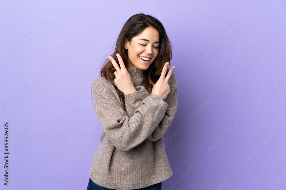 Woman over isolated purple background smiling and showing victory sign Woman over isolated purple background smiling and showing victory sign